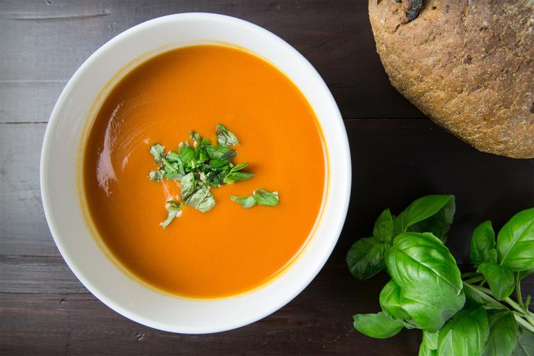 A bowl of roasted carrot soup sprinkled with herbs